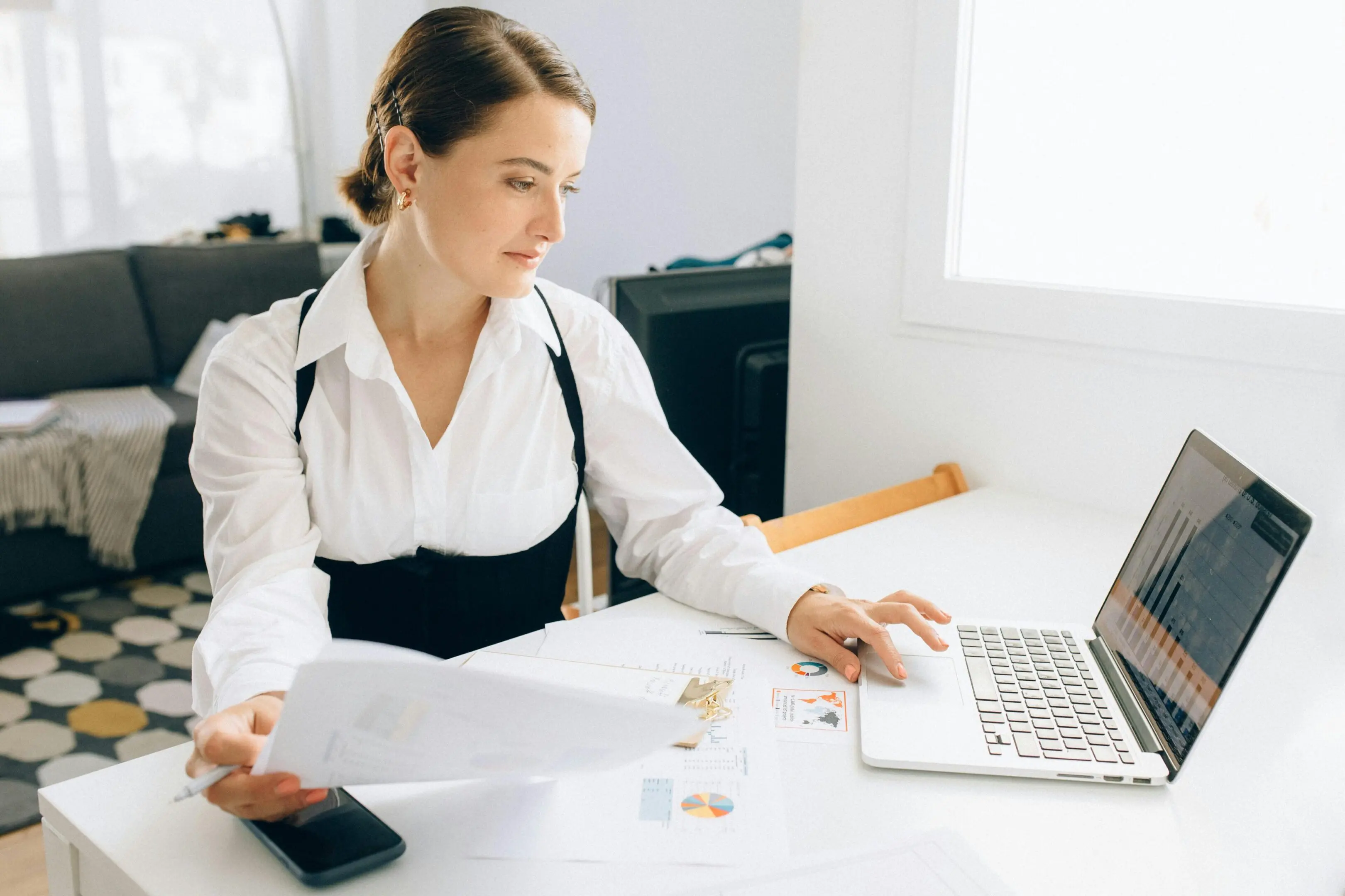 Woman working with laptop and documents.