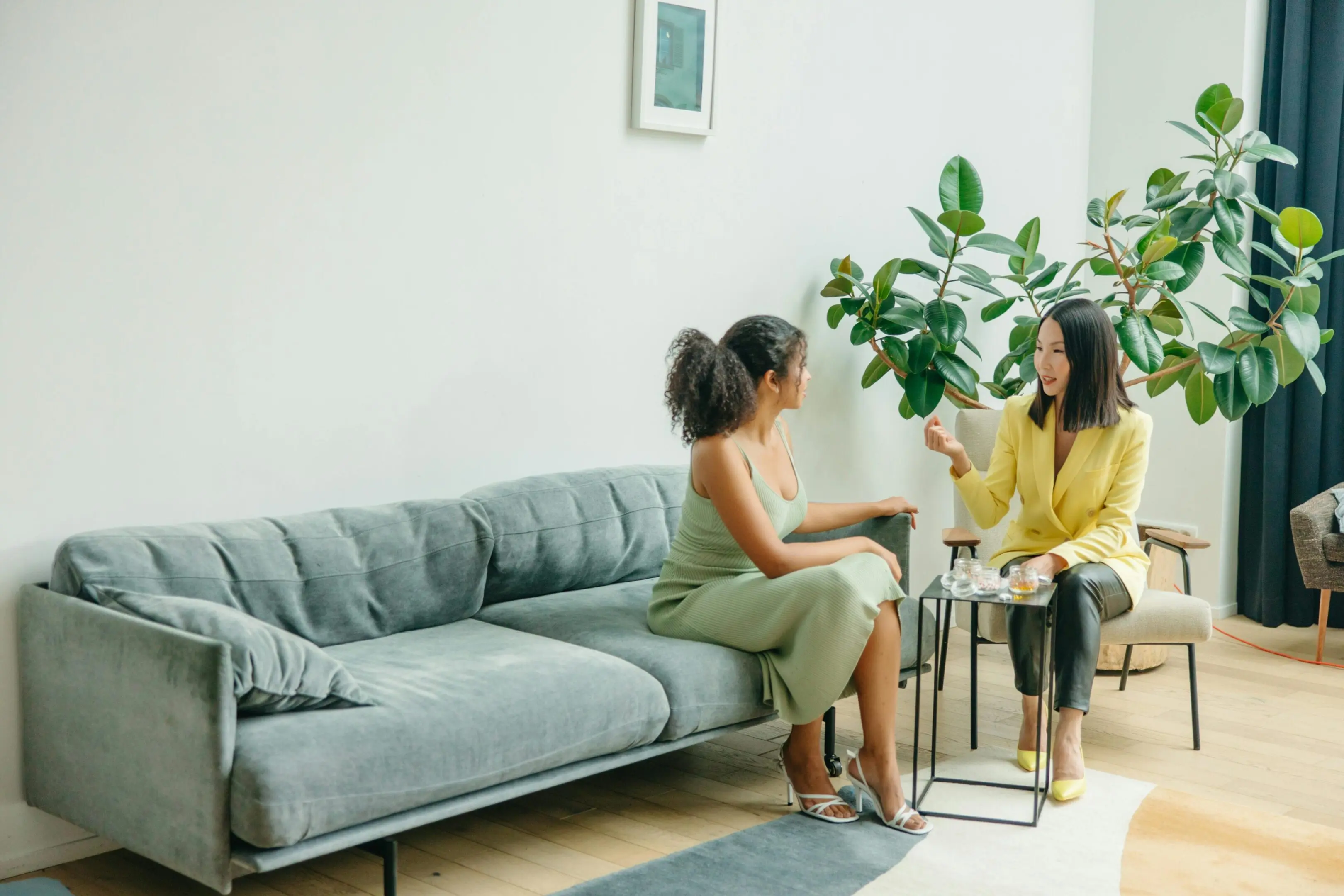 Two women talking on a living room sofa.