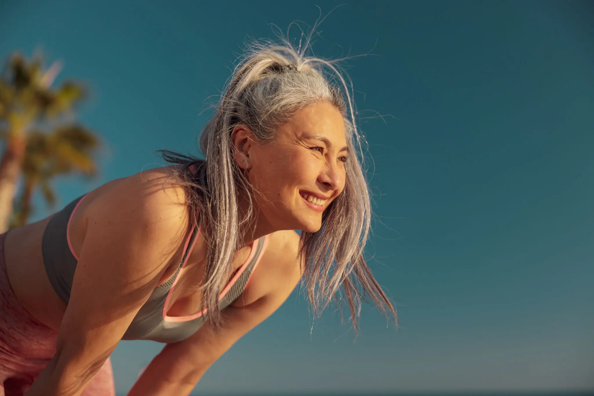 Smiling woman with silver hair enjoying a sunny day outdoors.