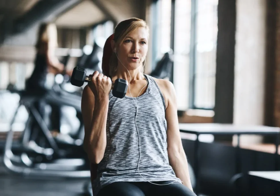 Woman lifting dumbbell in a gym.