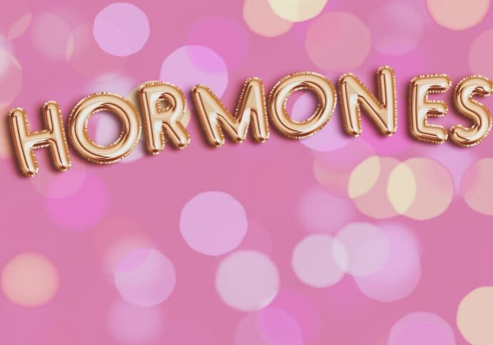 Gold "HORMONES" text on pink bokeh background.