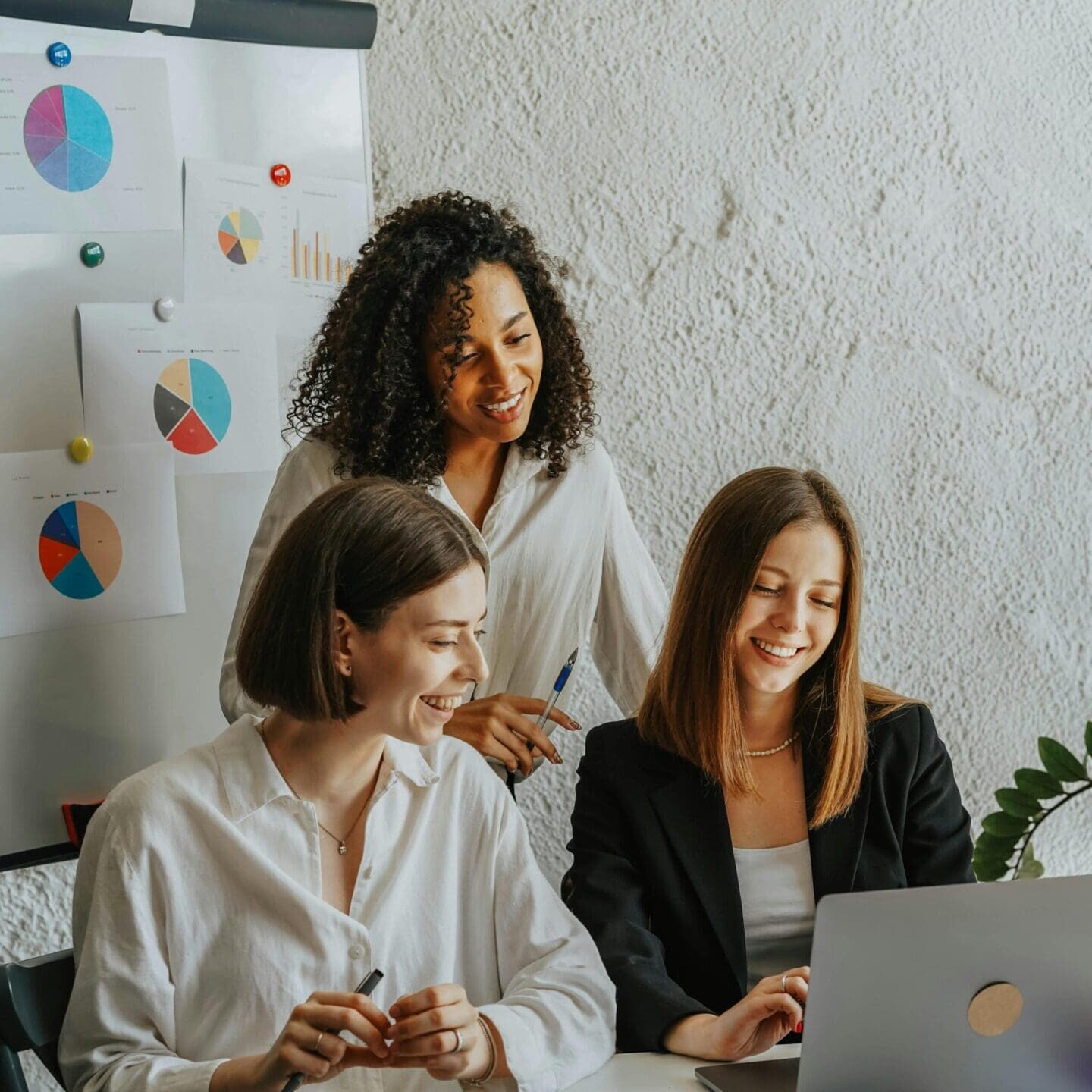 Three women collaborating in an office setting.